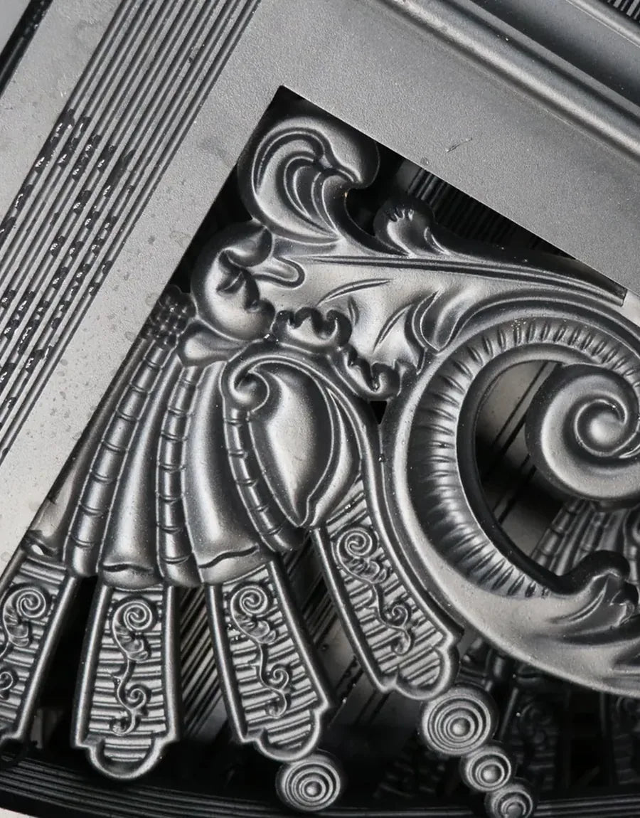 Close view of a cast aluminium scroll ornament, dark coated with the raised relief hand-highlighted in silver